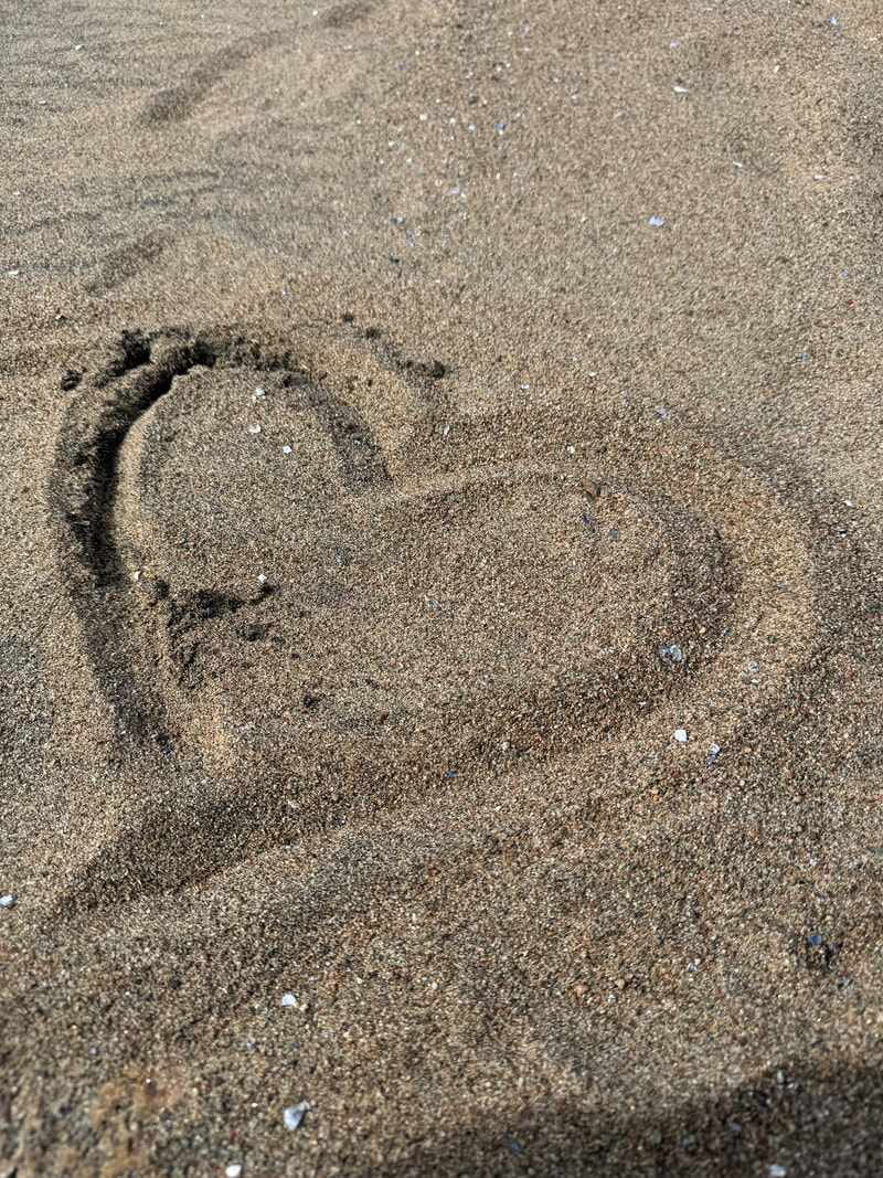 A heart is drawn in a beach covered with dark sand Picture